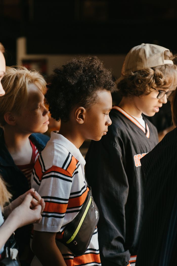 A multicultural group of teenagers standing together indoors, embracing diversity.